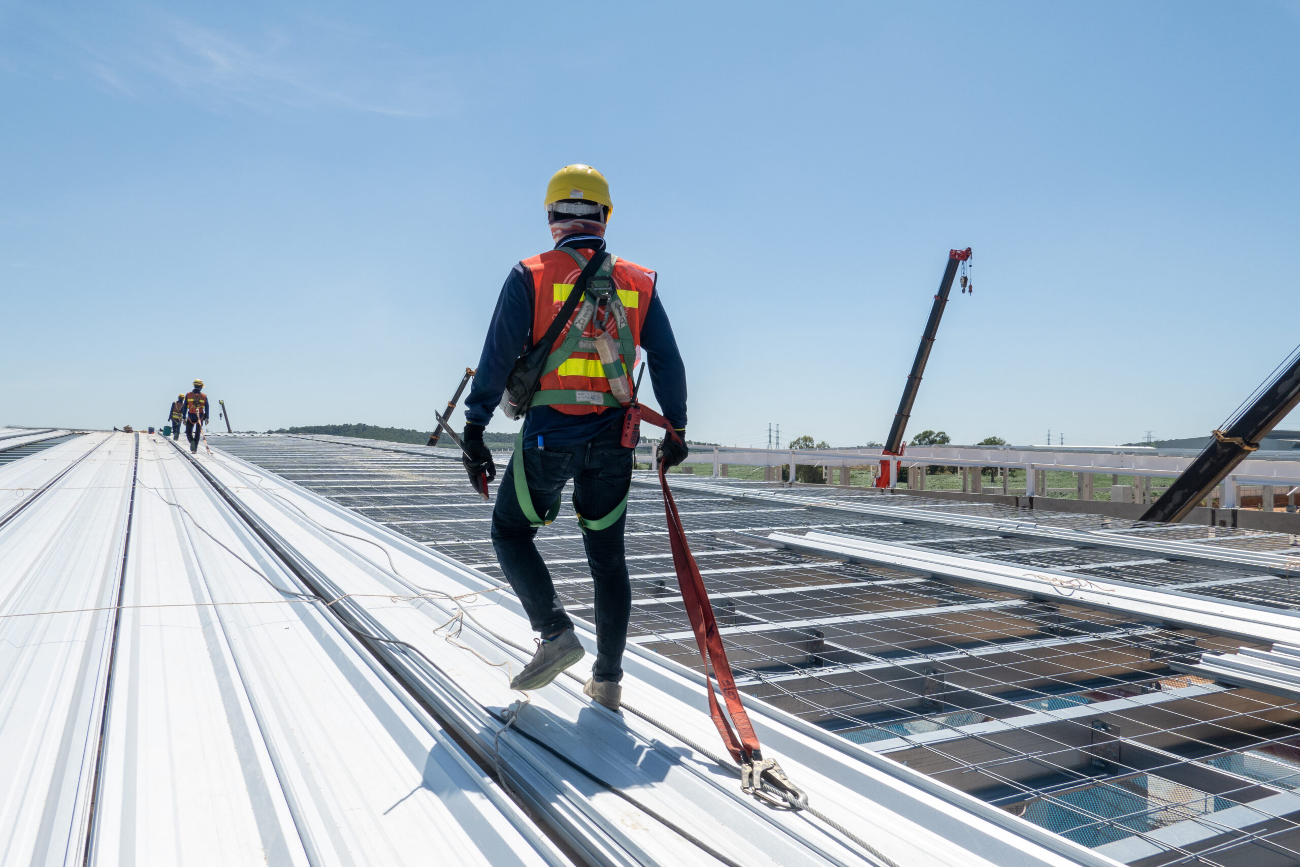Men walking on a roof on a construction site wearing safety gear